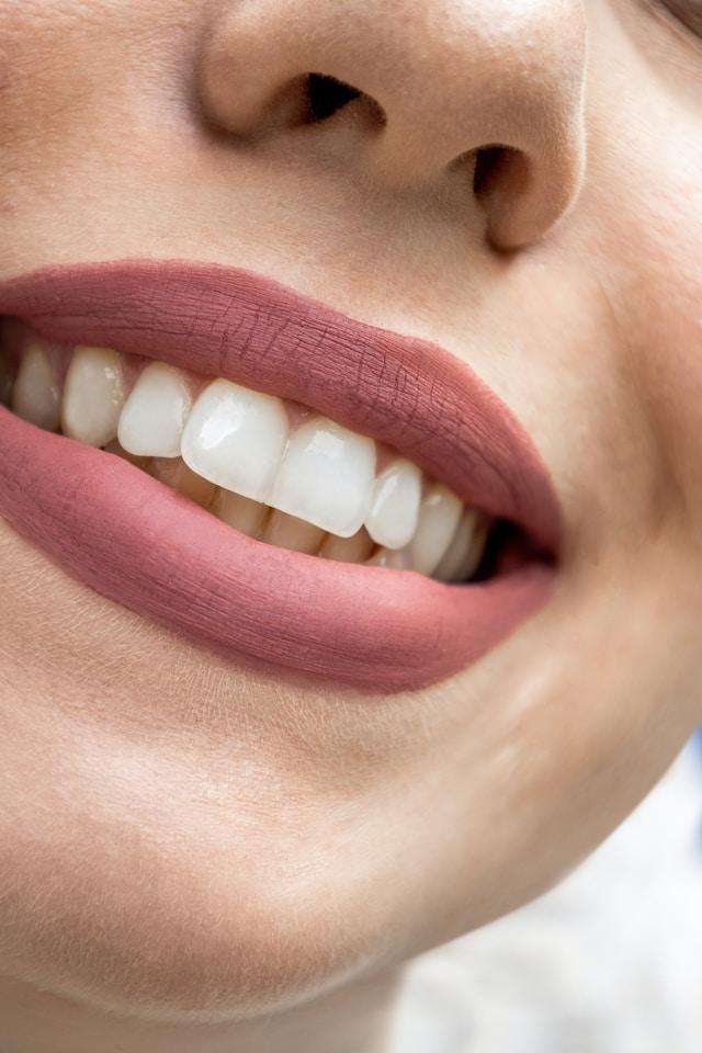 Bouche de femme avec rouge à lèvres qui sourit avec dents blanches