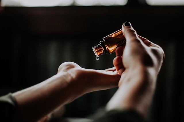 flacon en verre brun, tenu dans des mains de femme
