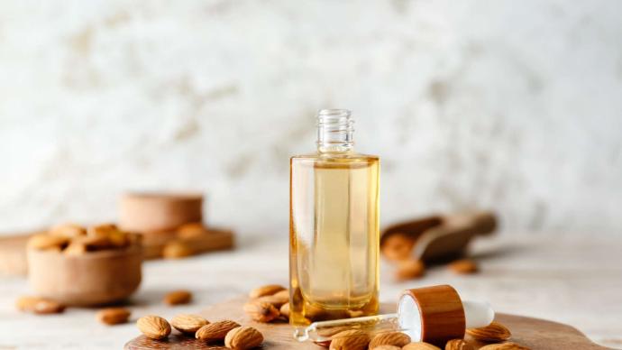 Flacon d'huile d'amande douce avec des amandes autour