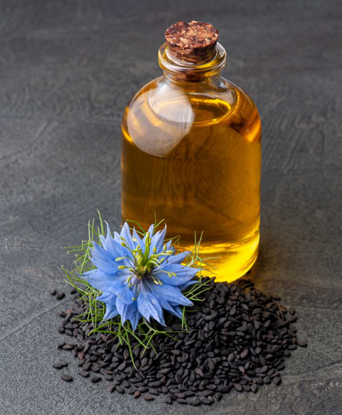 Flacon d'huile végétale avec à côté une fleur et des graines de nigelle 