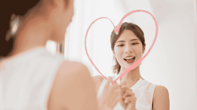 Jeune femme type asiatique qui dessine un cœur sur un miroir