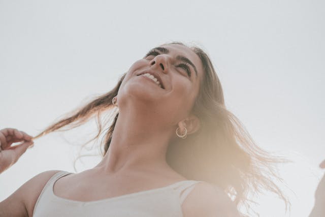 Femme cheveux longs et boucles d'oreilles qui sourit en regardant en l'air