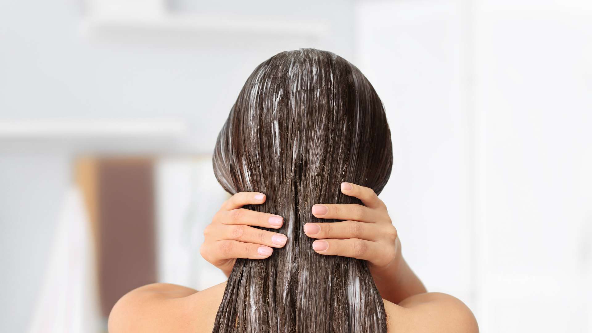 Femme de dos avec masque capillaire sur ses cheveux