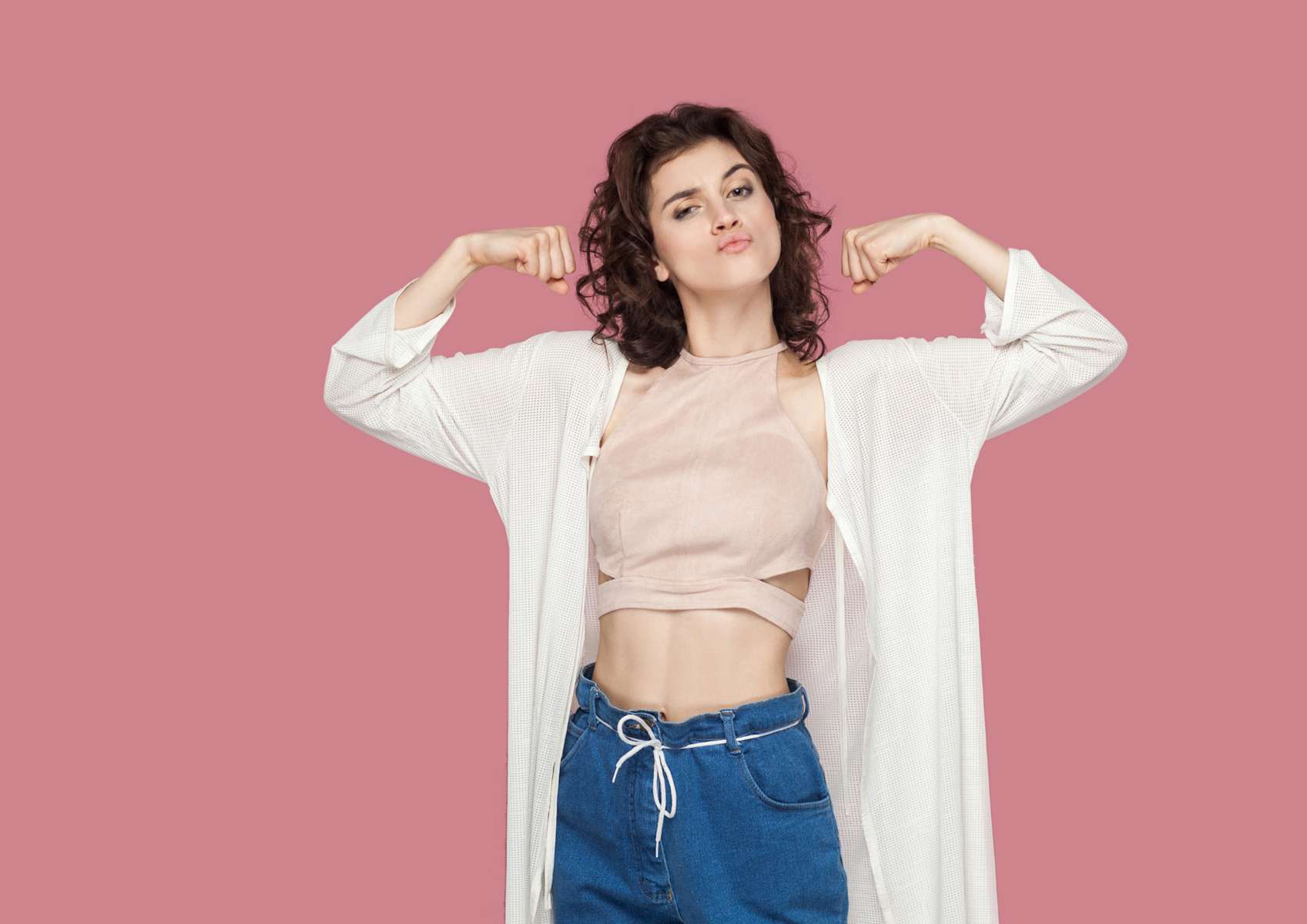 Jeune femme brune, bras contractés sur fond rose