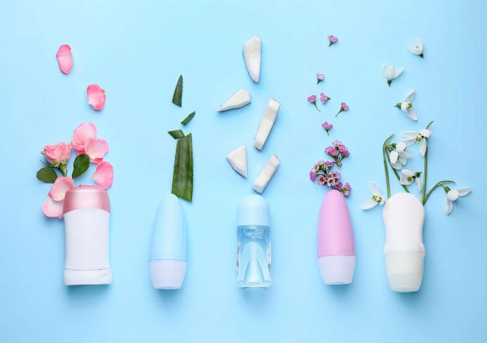 Cinq déodorants alignés avec des fleurs, aloe vera et morceaux de coix de coco sur fond bleu