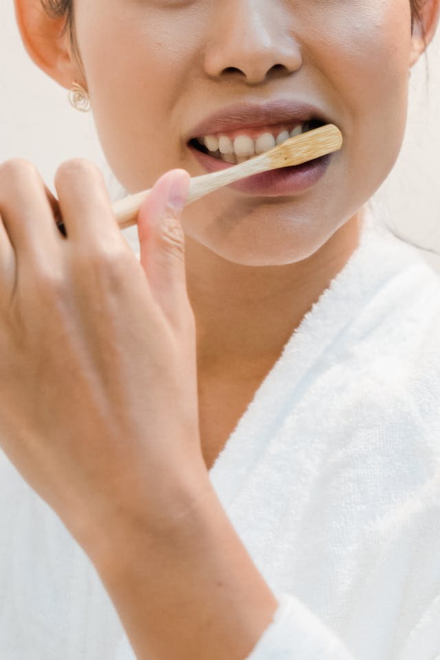 Visage femme en peignoir blanc qui se brosse les dents