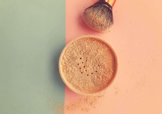 Poudre et pinceau de maquillage sur vert sauge à gauche et saumon ç droite