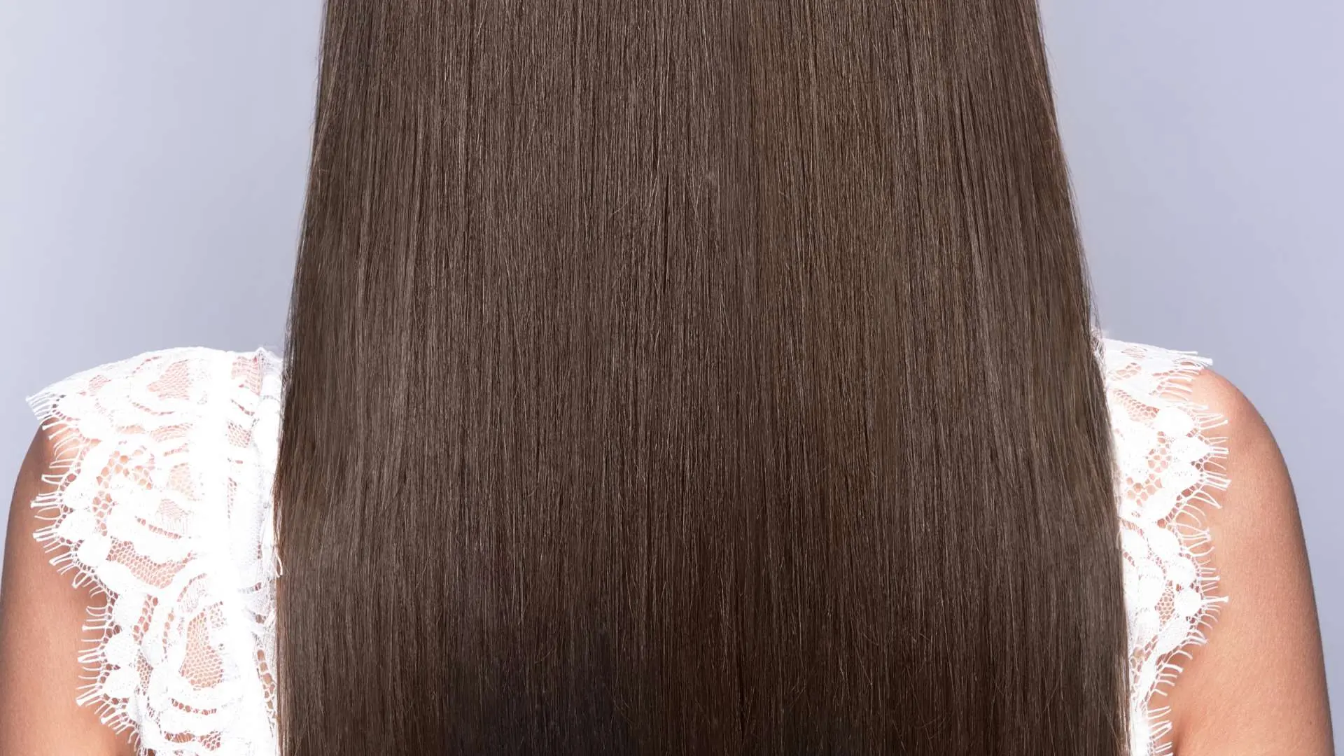 Cheveux longs bruns femme de dos avec haut débardeur en dentelle blanche